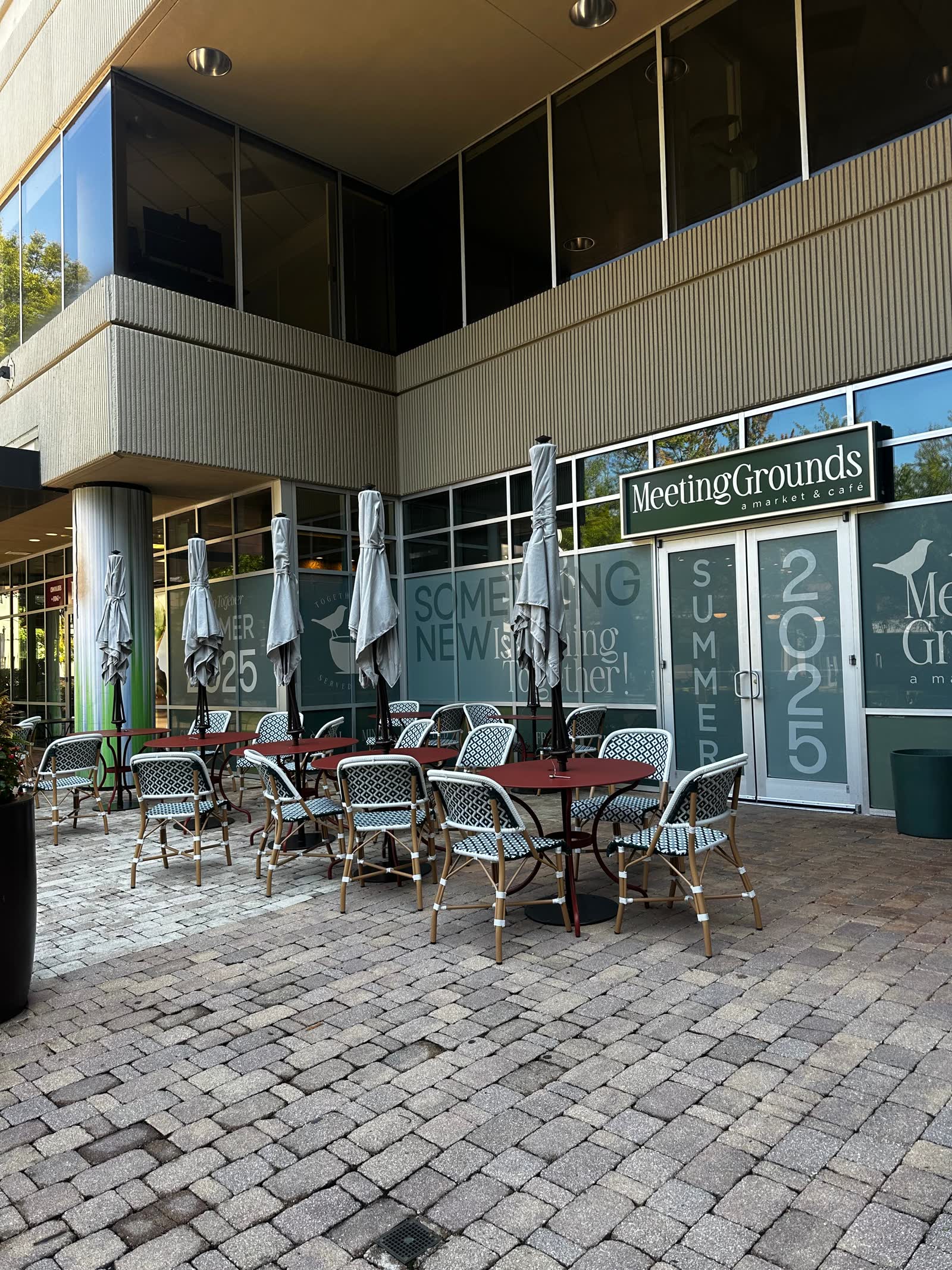 Meeting Grounds storefront with branded windows and outdoor cafe tables on a brick patio